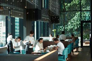 a group of people sitting at tables in a restaurant at The Gate Hotel Tokyo by Hulic in Tokyo
