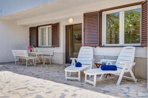a group of white chairs and a table on a patio at Deja near centar and Čikat bay with private parking in Mali Lošinj