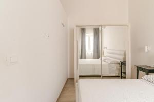 biała sypialnia z 2 łóżkami i lustrem w obiekcie La Casa di Nonna w mieście Ostuni +14 zdjęć