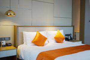 a bedroom with a large bed with two orange pillows at The QUBE Hotel Ningbo North in Ningbo