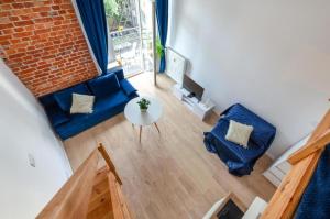 ein Wohnzimmer mit einem blauen Sofa und einem Tisch in der Unterkunft Centrum 2 Struga 46 in Łódź