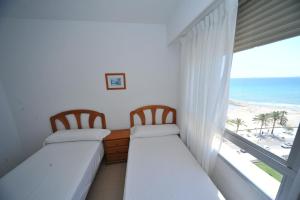 two beds in a room with a view of the beach at Castellmar vista mar Orangecosta in Benicàssim