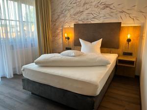 a bedroom with a large white bed with a wall at Hotel Schwaiger in Glonn