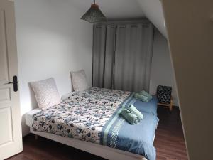 a bedroom with a bed with a blue comforter at Le gîte de la source in Cailly