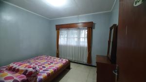 a bedroom with a bed and a window at Villa Putih in Songgoriti