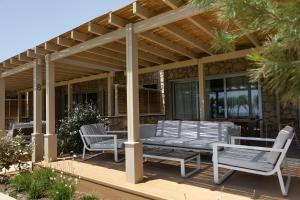 a pergola with two chairs and a bench on a patio at Elya Beach Luxury Suites in Ayios Theodhoros