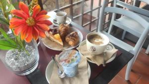 una mesa con un plato de comida y tazas de café en Hotel Arcobaleno Siena en Siena