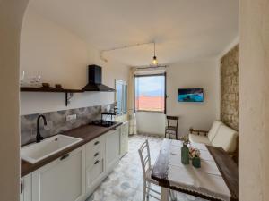 a kitchen with a sink and a table with a view at La casa di nonna Pietra in Baunei