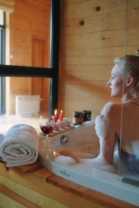a woman in a bath tub with a glass of wine at Elegant pet-friendly double villa, perfect for couples Svaneti Countryside 4 in Mestia +24 photos