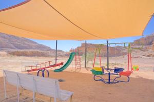 un parque infantil en el desierto con una sombrilla amarilla en Bilal luxury camp en Wadi Rum