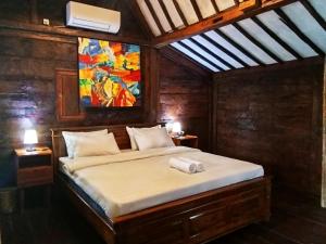a bedroom with a bed with a painting on the wall at Tahlia's Villa in Sorongjukung