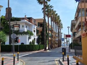 a street with palm trees and a white building at Rosalia Playa San Cristóbal WiFi NETFLIX in Almuñécar