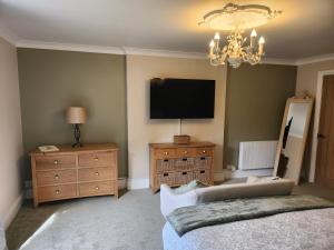 1 dormitorio con TV, 1 cama y vestidor en Hillarnias Tearoom and B&B en Shaftesbury