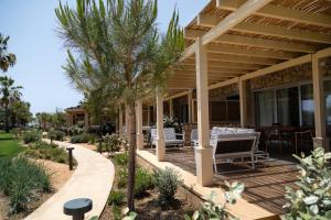 a patio with tables and chairs on a house at Elya Beach Luxury Suites in Ayios Theodhoros