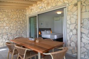 a dining room with a wooden table and a bedroom at Elya Beach Luxury Suites in Ayios Theodhoros