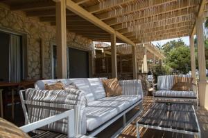 a porch with a couch and chairs on a patio at Elya Beach Luxury Suites in Ayios Theodhoros