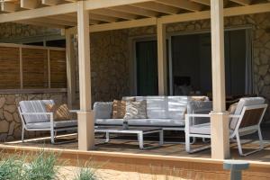 a porch with a couch and chairs on it at Elya Beach Luxury Suites in Ayios Theodhoros