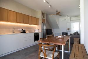 a kitchen with white cabinets and a wooden table at Elya Beach Luxury Suites in Ayios Theodhoros
