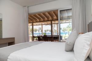 a bedroom with a bed and a view of the ocean at Elya Beach Luxury Suites in Ayios Theodhoros
