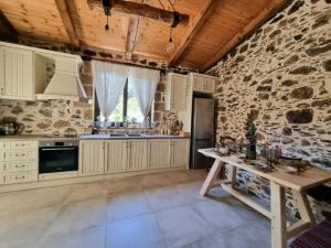 cocina con armarios blancos y pared de piedra en Mesavlia Traditional Stone House, en Mesávlia 43 fotos más