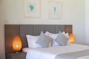 a bedroom with two beds with white pillows and two lamps at Elya Beach Luxury Suites in Ayios Theodhoros