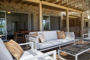 a patio with a couch and chairs and a table at Elya Beach Luxury Suites in Ayios Theodhoros