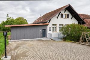 JeussHotel Jäger Jeuss - Murten - Self-Check-in的白色的房子,有棕色的屋顶和车道