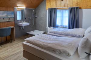 JeussHotel Jäger Jeuss - Murten - Self-Check-in的一间卧室设有两张床、淋浴和盥洗盆