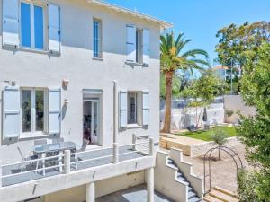 a white house with a porch and a palm tree at Maison Martel in Antibes