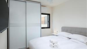 a bedroom with a white bed and a glass wall at Renovated 3BR Penthouse by HolyGuest in Tel Aviv