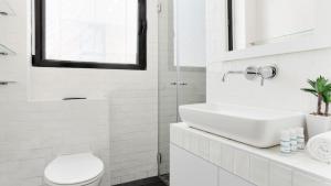 a white bathroom with a sink and a toilet at Renovated 3BR Penthouse by HolyGuest in Tel Aviv