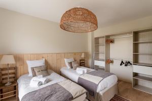a bedroom with two beds and a chandelier at La Cabane des Ebihens - A moins d'1km de la plage in Lancieux