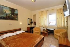 a bedroom with a large bed and a desk and chairs at Hotel Admitos in Volos