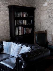 un sofá de cuero negro y una estantería con libros en The Crown at Marnhull en Sturminster Newton