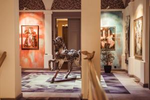 a statue of a horse in a hallway with paintings at Art Hotel Roma in Liepāja