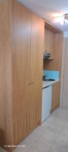 a kitchen with wooden cabinets and a sink and a dishwasher at Aegean Sun Hotel in Skala Rachoniou