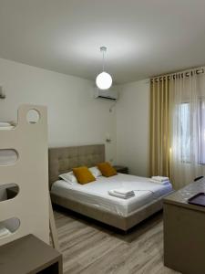 een slaapkamer met een bed met witte lakens en gele kussens bij Le Monde 2 in Borsh