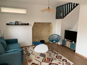 Maison rénovée au calme في Biéville-Beuville: غرفة معيشة مع أريكة وطاولة وتلفزيون