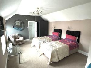 a bedroom with two beds and a chair at Ashfield Guesthouse in Douglas