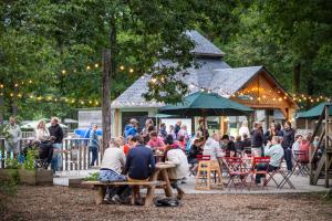 a group of people sitting at tables in a garden at Huttopia Lac de Sillé in Sillé-le-Guillaume