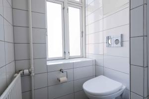 a white bathroom with a toilet and a window at Lovely 3BR Manor Flat 5 min from Tivoli Gardens in Copenhagen