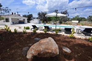 einen Hof mit einem großen Felsen und einem Pool in der Unterkunft Villa Myricae in San Vito dei Normanni