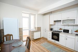 a kitchen with white cabinets and a table in it at Retreat relaxant cu 2 dormitoare! in Chişinău