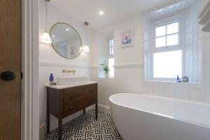 a bathroom with a tub and a sink and a mirror at 11 Tywarnhayle House, Perranporth in Perranporth +19 photos