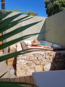 博尼法喬的住宿－Hôtel Les Suites Du Maquis，身着帽子的人躺在热水浴缸中