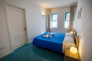 a bedroom with a blue bed and a door at Villa Tre Mari in Villasimius