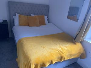 um quarto com uma cama branca e um cobertor amarelo em The Cosy Nook em Blackpool