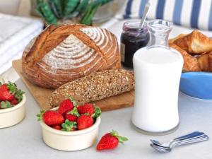 - une table avec du pain, des fraises et une bouteille de lait dans l'établissement Villa Mare, Mykonos, à Kalafatis