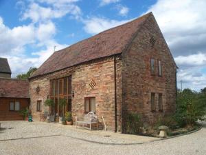 an old brick building with a bench in front of it at Bridge Farm Holiday Cottages in Cow Honeybourne