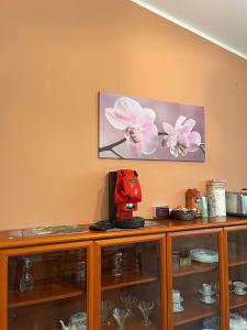 a wooden cabinet with glass shelves and a picture of flowers at ROOM365 in Lanciano